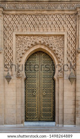 Traditional Moroccan style design of an ancient wooden entry door. In the old Medina in Marrakech, Morocco. Typical, old, brown intricately carved, studded, Moroccan riad door