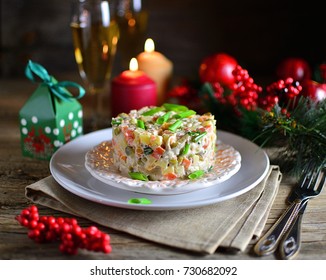 Traditional New Year and Christmas salad on holiday, on a plate, winter, New Year's still-life with champagne and candles, old wooden background, rustic
