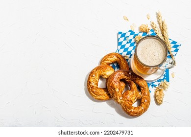 Traditional Oktoberfest set. Pretzels, beer, traditional pattern napkin. German festival food concept. Trendy hard light, dark shadow, white putty background, top view