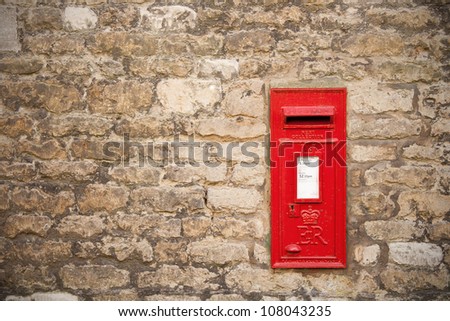traditional old English red postbox mounted in a cotswold stone wall