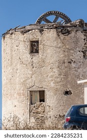 Traditional old Greek windmill, ruined in sunny sky with wooden construction inside and cracked wall