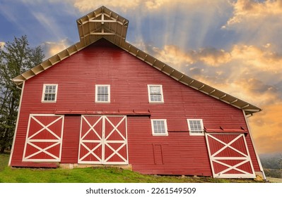 Traditional old red barn with white windows and doors with sunrise sun rays sky. - Powered by Shutterstock