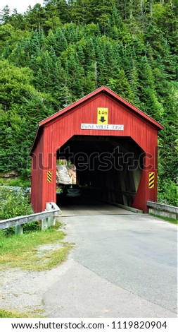 A traditional old red wooden covered bridge in Fundy National Park, New Brunswick Canada on a sunny summer day. 
