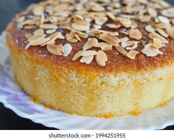 Traditional one whole round French almond cake with crumby texture topped with toasted crunchy almond slices drizzled with orange sauce
