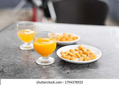 Traditional orange drink from Madeira poncha with a snack lupines "tremoços" in a bar outdoors 
