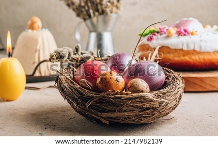 Traditional Ortodox Easter background. Easter eggs in a nest on a stone background. Easter curd cake, Easter kulich and colored eggs. Selective focus
