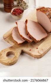 Traditional oven baked bavarian meal leberkäse sliced - meat dish made of corned beef, pork and bacon, finely ground and bakes as a bread loaf, on wooden board on beige colored table cloth - Shutterstock ID 2176066867
