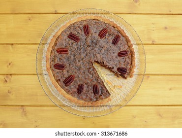 Traditional pecan pie topped with toasted nuts with a slice missing