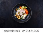 Traditional Peruvian gourmet ceviche sea bass filet piece with sweet potatoes and cancha marinated and served in lime sauce as top view in a modern design bowl with copy space