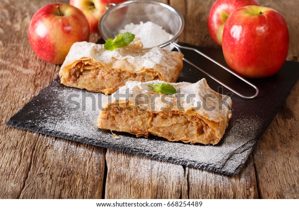 Traditional piece of apple strudel\
with powdered sugar and mint closeup on a table.\
horizontal\
