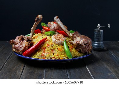 Traditional Pilaf With Loin Chops Lamb On Plate On Wooden Table, Black Background. Side View.