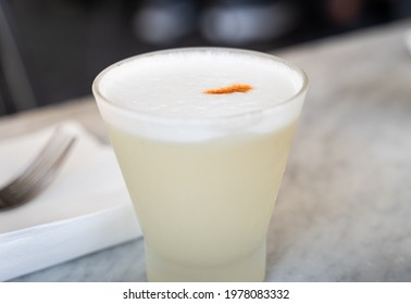 Traditional Pisco Sour Peruvian Drink With Angostura Bitters On Top. Closeup On Alcoholic Glass On Table