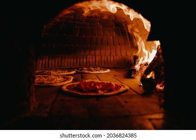 traditional Pizza Oven with big flames and pizzas in the oven