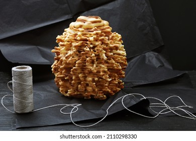 Traditional Polish, Lithuanian layered, sweet cake on black paper background. Composition with original spit baked dessert. Tree cake, anthill. Golden sekacz, regional delicacy, sakotis, raguolis.