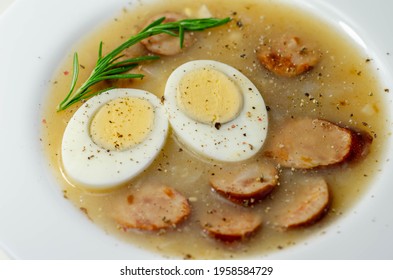 Traditional Polish Sour Soup With Sausage And Eggs In A White Deep Plate, Eastern European Meal