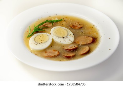 Traditional Polish Sour Soup With Sausage And Eggs In A White Deep Plate, Eastern European Meal