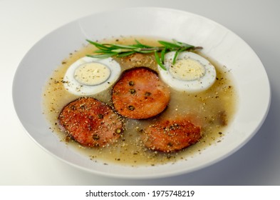 Traditional Polish Sour Soup With Sausage And Eggs In A White Deep Plate, Eastern European Meal