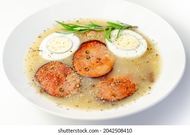 Traditional Polish Sour Soup With Sausage And Eggs In A White Deep Plate, Eastern European Meal