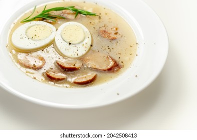 Traditional Polish Sour Soup With Sausage And Eggs In A White Deep Plate, Eastern European Meal