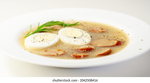 Traditional Polish Sour Soup With Sausage And Eggs In A White Deep Plate, Eastern European Meal