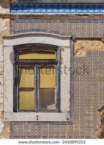 Traditional Portuguese architecture. Old abandoned house with window and exterior wall with colorful ceramic tiles. Vintage facade of building with damaged Azulejo tiles.