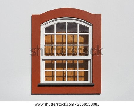 Traditional Portuguese house. Part of white wall with white wooden window and brown orange window frame. Angra do Heroísmo, Terceira Island, Portugal.