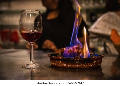 Traditional Portuguese Sausage Chourico Aka Spanish Chorizo Sliced And Flame-cooked Over Alcohol In An Earthenware Dish Served With A Glass Of Chilled Red Port Wine, A Fado House, Lisbon,