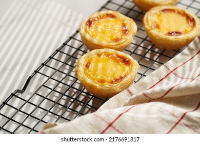 Traditional Portuguese Vanilla Pudding Puff Pastry Pastel De Nata On Black Oven Rack On Marble Background With Checkered Kitchen Towel