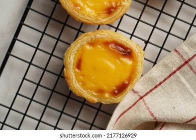 Traditional Portuguese Vanilla Pudding Puff Pastry Pastel De Nata On Black Oven Rack On Marble Background With Checkered Kitchen Towel