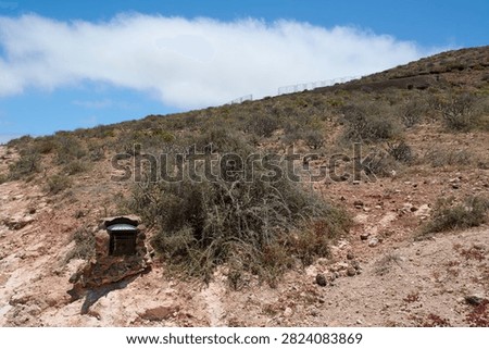 A traditional post box built into a stone pedestal near arid vegetation on a sunny day in Gran Canaria.