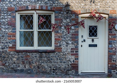 Traditional pretty and cosy English brick and flint terraced cottage with Union Jack bunting on display