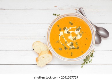 Traditional Pumpkin Soup With Cream, Seeds And Herbs. Overhead Table Scene On A White Wood Background.