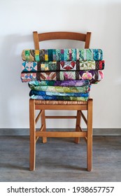 Traditional Quilts Stacked On Wooden Chair Against Neutral Wall