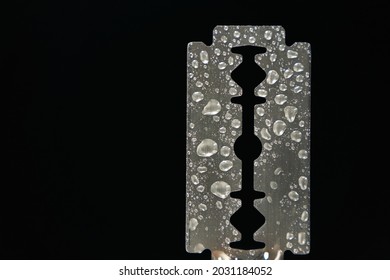 Traditional razor blade with water droplets on black background. Macro shooting