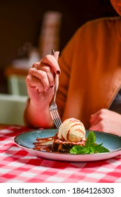 Traditional Recipe Brownie With Ice Cream Served On A Blue Plate Over Table With Red Plaid Tablecloth. Italian Cuisine Concept, Sweet Dessert. Young Woman Eating Chocolate Brownie And Ice Cream.