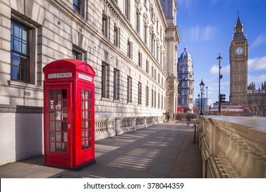 Traditional red british telephone box with Big Ben and Double Decker bus at the background on a sunny afternoon with blue sky and clouds - London, UK