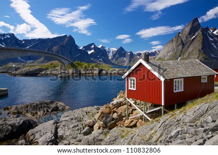 Traditional red fishing rorbu hut on Lofoten islands in Norway near bridge connecting islands