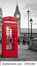A  traditional red phone booth in London with the Big Ben in a black and white background