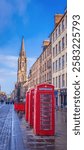 Traditional red telephone kiosks standing on famous Royal Mile in Edinburgh. Beautiful old city centre with historic buildings and local shops.