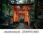 Traditional red torii gates at Fushimi Inari Shrine in Kyoto, Japan, surrounded by lush green forest, creating a serene atmosphere.