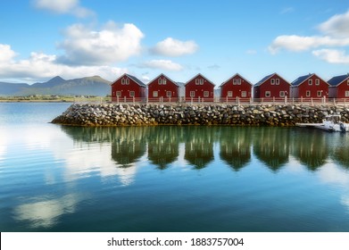 Traditional red wooden houses on the shore of Offersoystraumen fjord. Fantastic summer sunset on Vestvagoy island. Picturesque evening view of Lofoten Islands, Norway, Europe. Life over polar circle