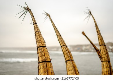 Traditional reed boats Caballitos de totora on the beach with the view on the pacific ocean with waves and the coast - Huanchaco, Trujillo, Peru