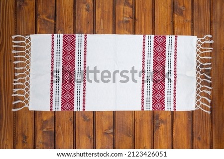 Traditional Romanian napkin or dish towel on empty wooden table. Traditional motif. Top view.