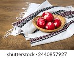 Traditional Romanian red Easter eggs decorated with leaves and boiled in onion peels on a wooden table