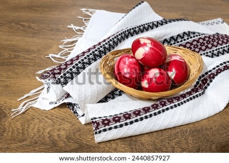 Traditional Romanian red Easter eggs decorated with leaves and boiled in onion peels on a wooden table