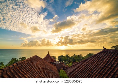 Traditional roofs of Balinese houses against the backdrop of the ocean and dawn in Amed, Bali, Indonesia