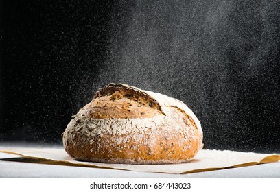 traditional round artisan rye bread loaf with walnut and seeds was sprinkled flour on wooden cutting board. Dark background  - Powered by Shutterstock