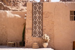 Traditional Rug And A Wicker Floor For Serving Food Hanging On An Old Mud Wall In "Al Ola" Al Ula, Saudi Arabia. Al Ola Is Part Of Madinah Province In Western Saudi Arabia