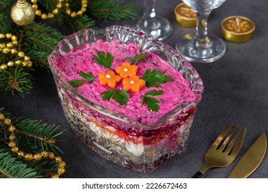 Traditional Russian holiday salad Herring under a fur coat in transparent salad bowl on dark gray background