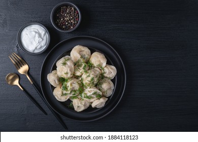 Traditional russian pelmeni, ravioli, dumplings with meat on black background. Top view. Copy space. Banner.	